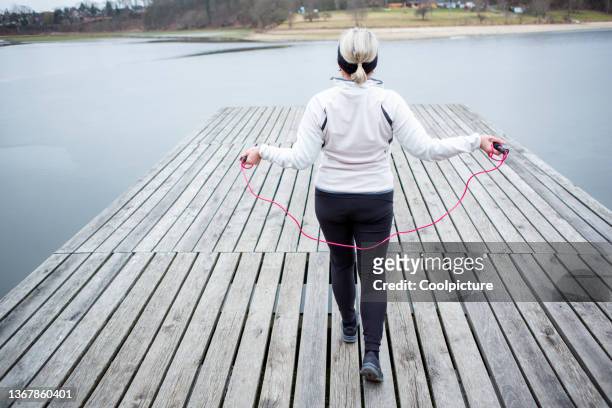 mature woman exercising outdoors. - touwtje springen stockfoto's en -beelden