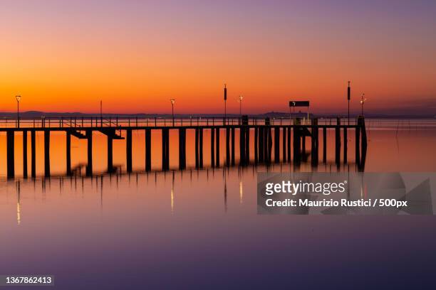 magic sunset,silhouette of pier on sea against sky during sunset,lago trasimeno,provincia di perugia,italy - lac trasimeno photos et images de collection