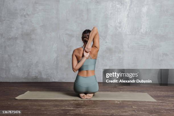 back yogi woman doing yoga exercises on the floor sitting with hands together. - human back stock pictures, royalty-free photos & images