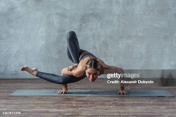 athletic strong woman doing yoga exercise pose standing on hands. - elastisch stock-fotos und bilder