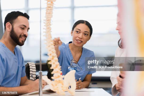female medical student asks teacher question while male friend listens - studie-geneeskunde stockfoto's en -beelden