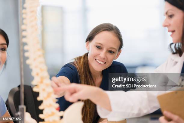 medical school student and professor discuss human spine model - fisiologia imagens e fotografias de stock