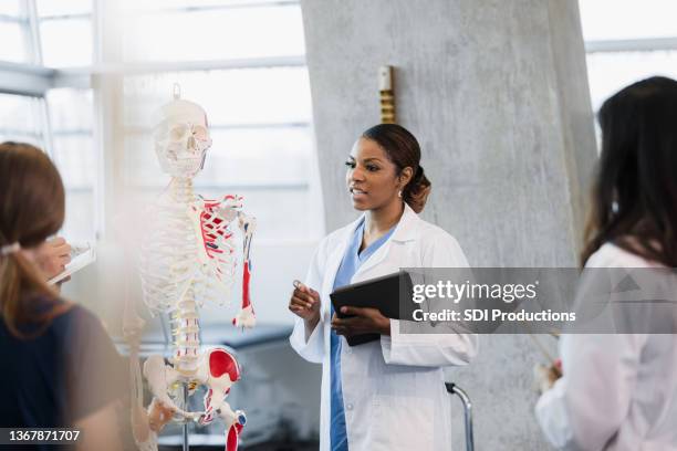 female medical school professor answers unseen student's question - fisiologia imagens e fotografias de stock