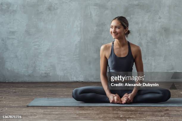 happy yogi woman practicing yoga sitting on the floor in butterfly pose. - mat stockfoto's en -beelden