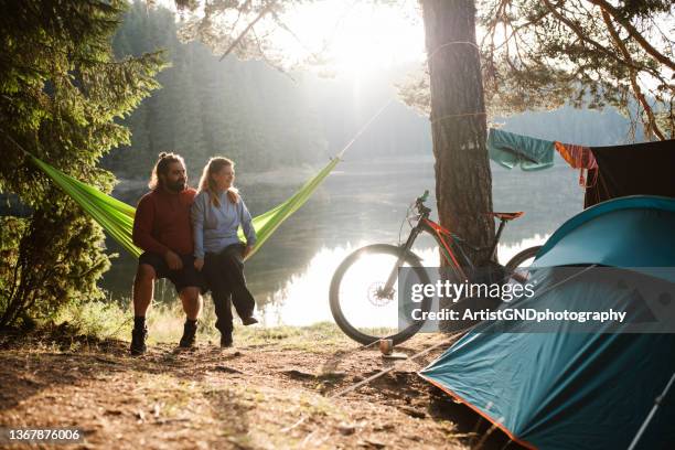 young couple enjoying beautiful morning at camping. - hammock camping stock pictures, royalty-free photos & images