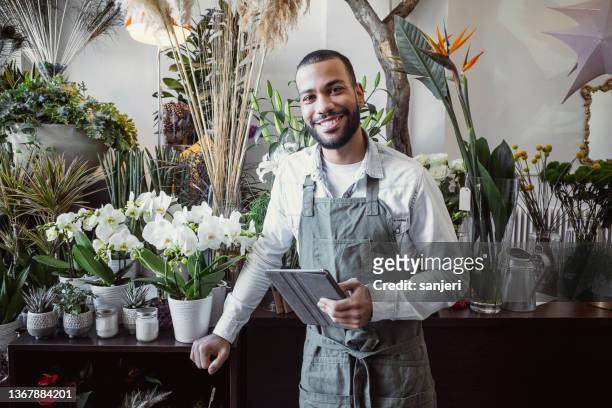 portrait of a florist working in the flower shop - flower shop stockfoto's en -beelden