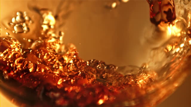 Cognac pours a whirlpool into a glass. Filmed is slow motion 1000 fps.