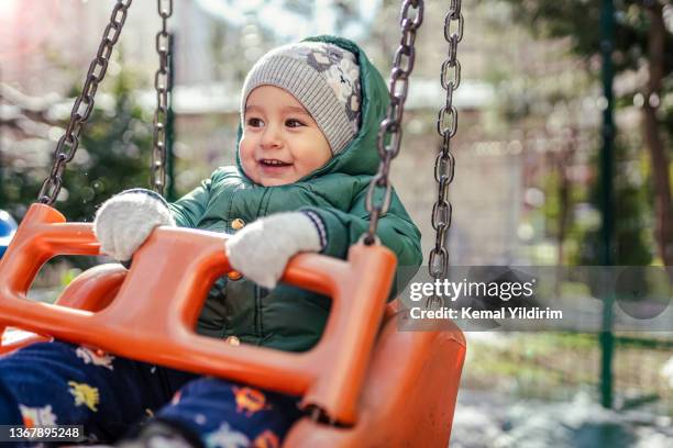 baby boy swinging at backyard in winter season - carrousel gardens stock pictures, royalty-free photos & images