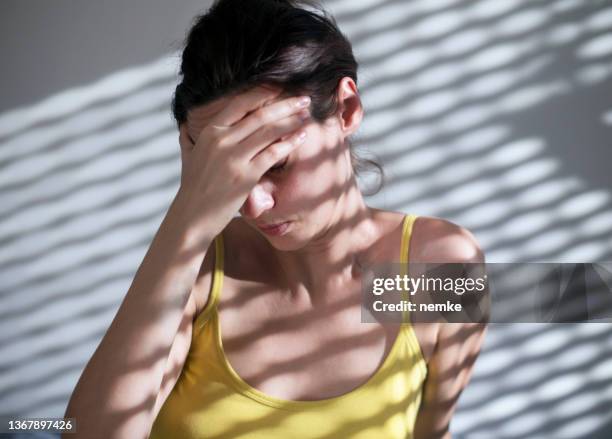 woman suffering from headache sitting on floor - pijnstiller stockfoto's en -beelden