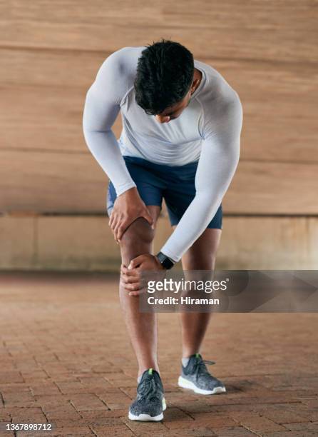 shot of a sporty young man experiencing knee pain while exercising outdoors - strength stock pictures, royalty-free photos & images