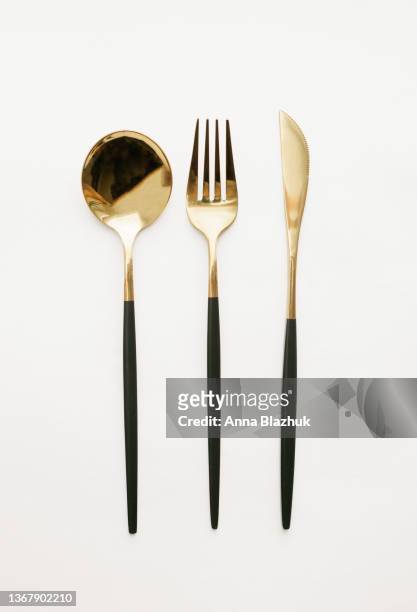 black and golden fork, knife and spoon over white background - fork photos et images de collection