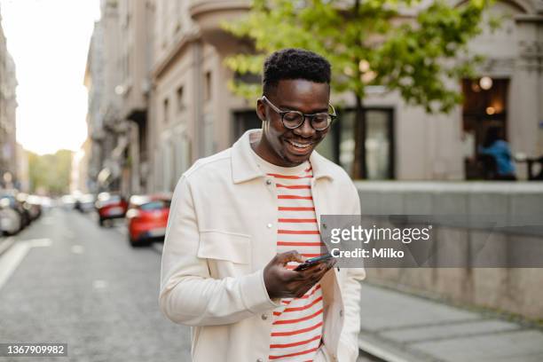 giovane afroamericano usa un cellulare in movimento - single foto e immagini stock