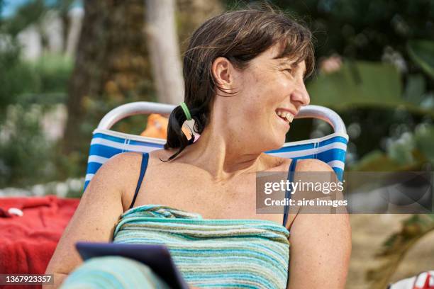woman smiling and relaxing while sitting next to a pool. - envuelto en una toalla fotografías e imágenes de stock