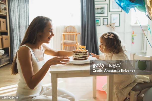 young girl with his mother blowing candles for celebreating her 2th years birthday. - build presents the family stock pictures, royalty-free photos & images