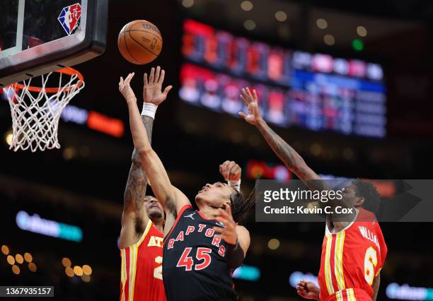 Dalano Banton of the Toronto Raptors has this shot blocked by John Collins of the Atlanta Hawks during the first half at State Farm Arena on January...