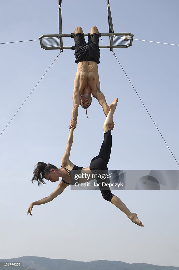 Male and female acrobats perform high on trapeze