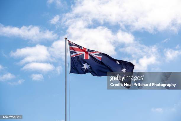 the australian flag flying against a blue sky - australia flag stock pictures, royalty-free photos & images