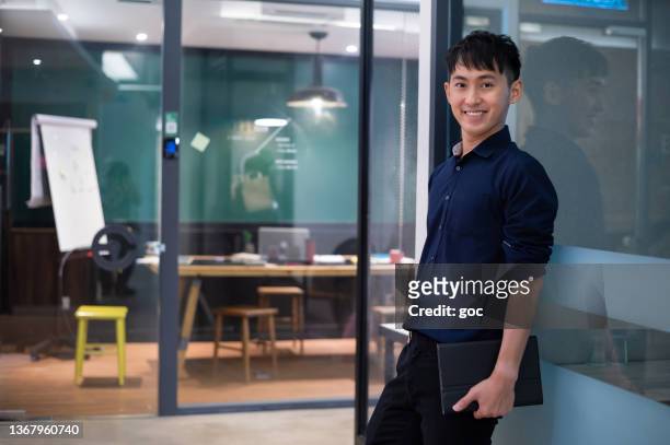 smiling male business executive with digital tablet in modern office - staff wellbeing stock pictures, royalty-free photos & images