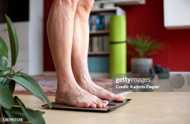 man standing on weight scale, low section - jeûner photos et images de collection