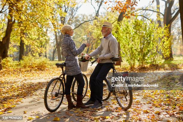 senior couple with the bicycles in the park - adult riding bike through park stock pictures, royalty-free photos & images