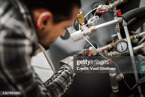 Ingeniero de calefacción arreglando el sistema de calefacción moderno. Ingeniero de calefacción arreglando el sistema de calefacción moderno.