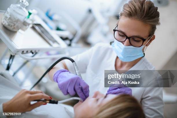dentist repairing the patient's teeth in the dental office. - dental drill stock pictures, royalty-free photos & images