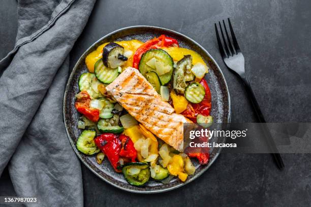 roasted salmon with vegetables - crockery fotografías e imágenes de stock