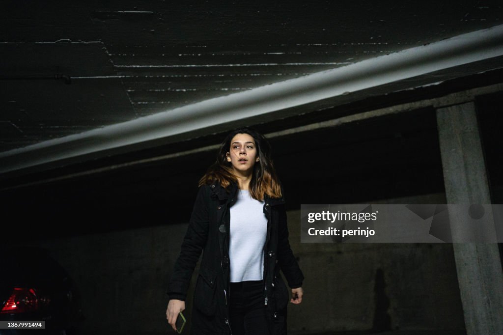 Caucasian teenage girl in fear running at the parking escaping from abuser