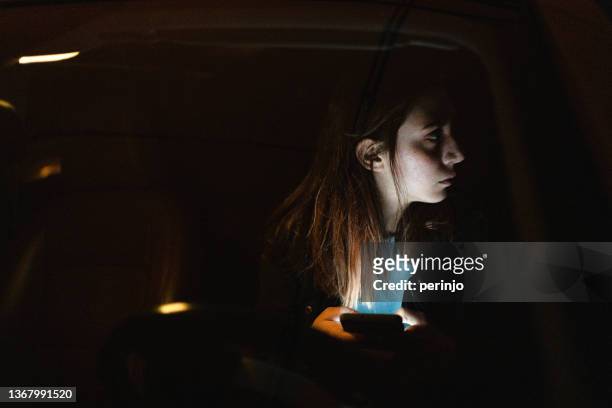 absued teenage girl, looking over shoulder from her car window - abuse victim stock pictures, royalty-free photos & images