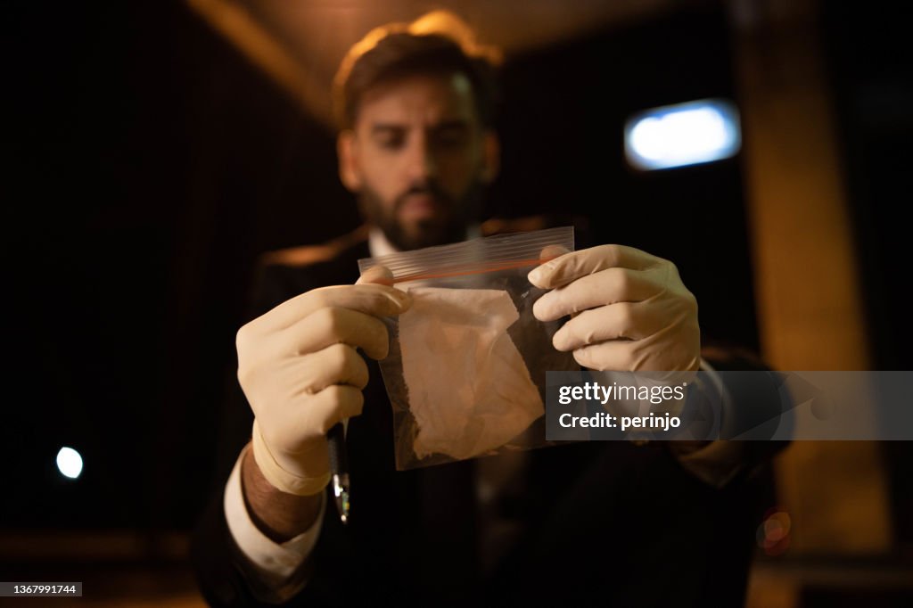 Sulla scena del crimine detective forense che osserva le prove nel sacchetto di plastica
