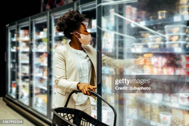 young woman wearing a protective mask in a supermarket. - dairy aisle stock pictures, royalty-free photos & images