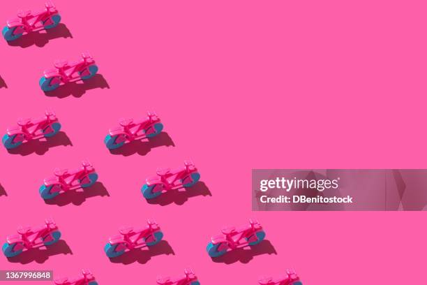 pattern of pink toy bicycles with blue wheels, with hard shadow, on the left side, on pink background. concept of toy, bicycle, exercise, minimalism, transportation and play. - fahrrad sattel stock-fotos und bilder