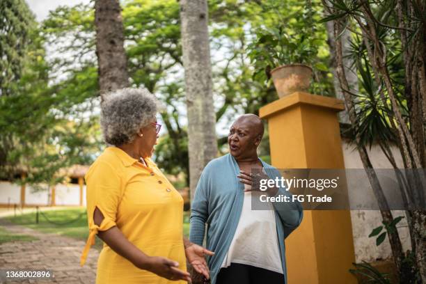 mujeres mayores hablando y caminando al aire libre - verguenza fotografías e imágenes de stock
