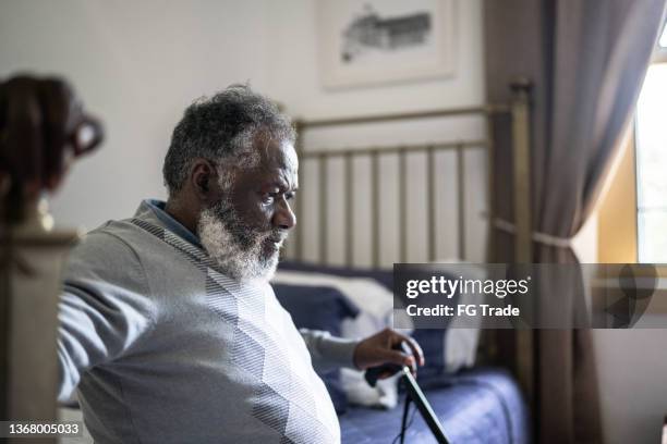 contemplative senior man sitting in the bed at home - african american man depressed bildbanksfoton och bilder