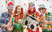 Happy dressed people celebrating at carnival party throwing confetti - Focus on left girl hands