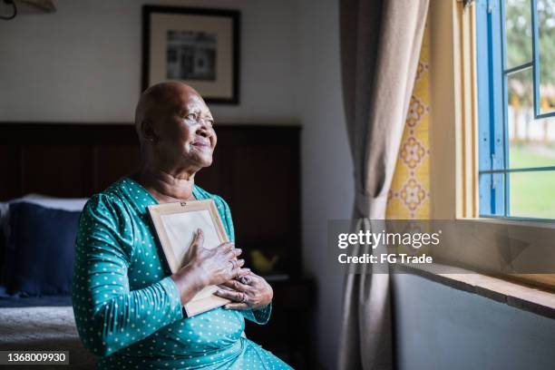 donna anziana che tiene una cornice mancante di qualcuno a casa - vedova foto e immagini stock