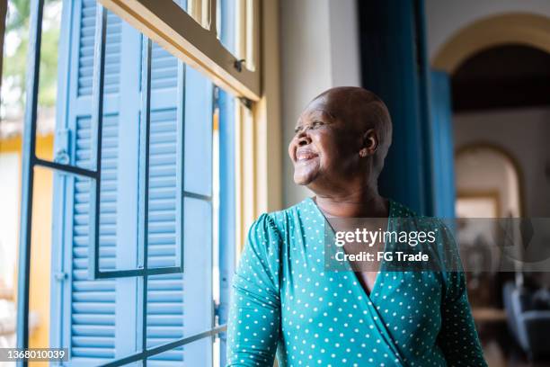 mulher sênior contemplativa olhando pela janela - careca - fotografias e filmes do acervo