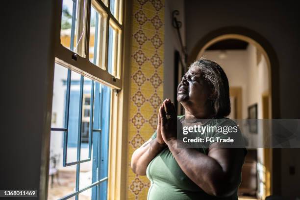 senior woman praying at home - patience please stock pictures, royalty-free photos & images