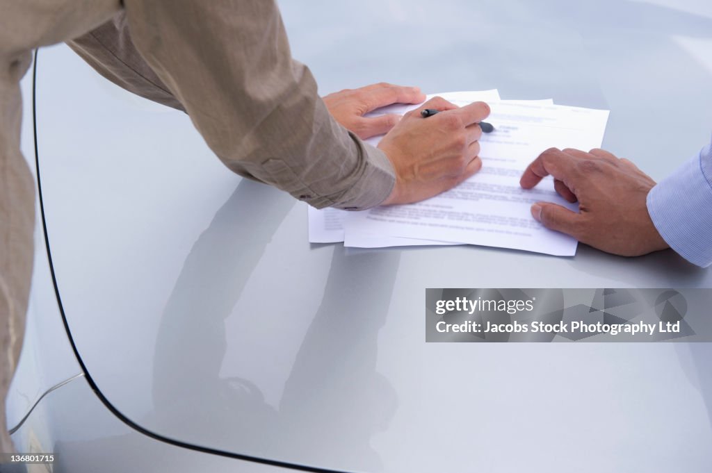 Business people looking at paperwork in parking lot