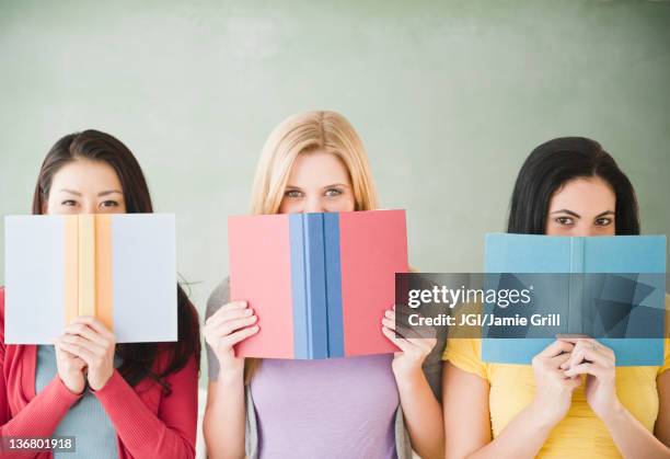 women hiding behind books - peeking over stock pictures, royalty-free photos & images