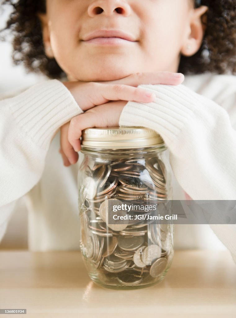 African American girl holding jar of coins
