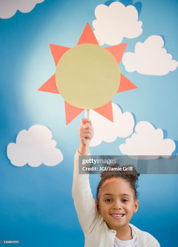 African American girl holding up paper sun