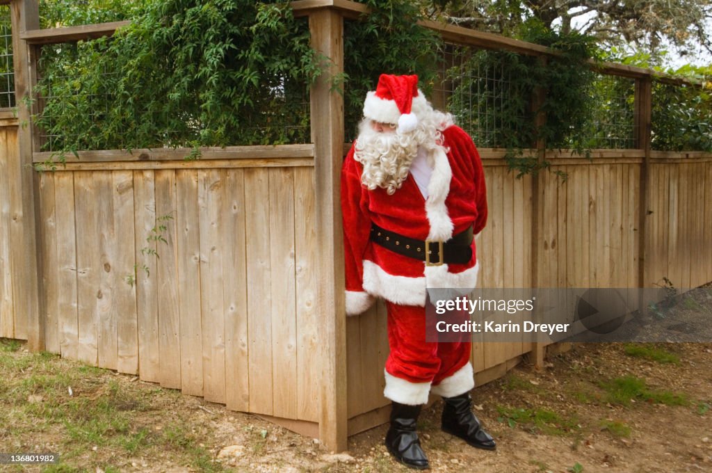 Santa hiding behind fence