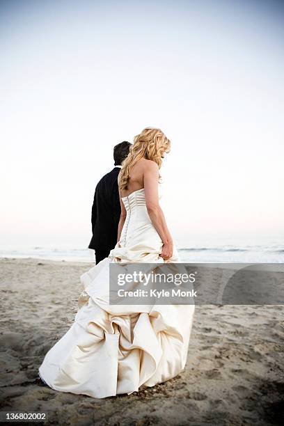 bride and groom walking on beach - bride walking stock pictures, royalty-free photos & images