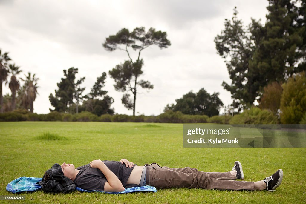 Caucasian man laying in grass in park