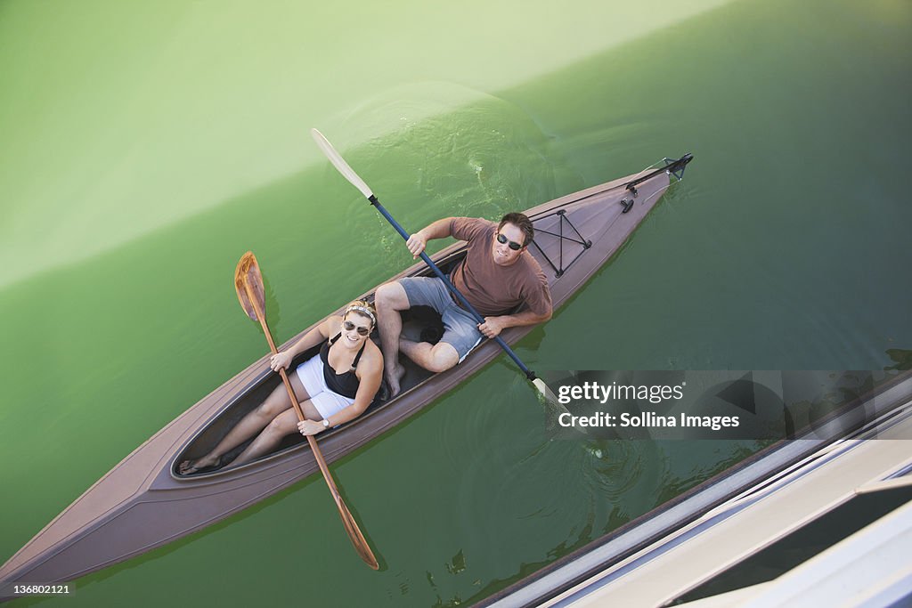 Caucasian couple rowing canoe