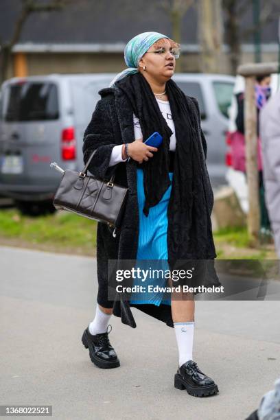 Guest wears a blue and white print pattern silk scarf, a black long scarf, a white with black inscriptions print pattern t-shirt, a black long fluffy...