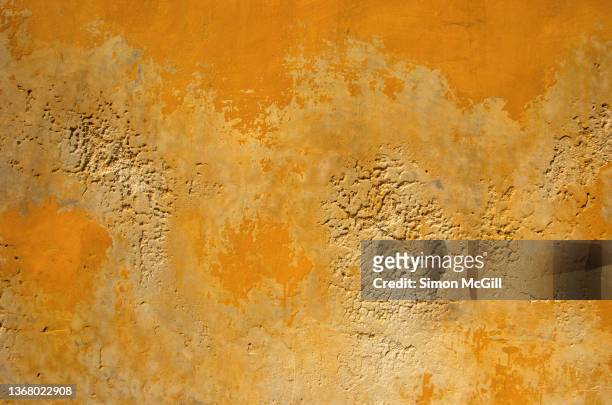 peeling and faded paint on an eroded stucco and adobe building exterior wall - ugly wallpaper stock pictures, royalty-free photos & images