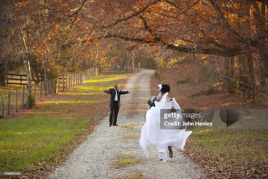 African American bride and groom running to each other on path