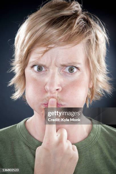 caucasian woman holding finger over her mouth - woman with finger on lips stock pictures, royalty-free photos & images